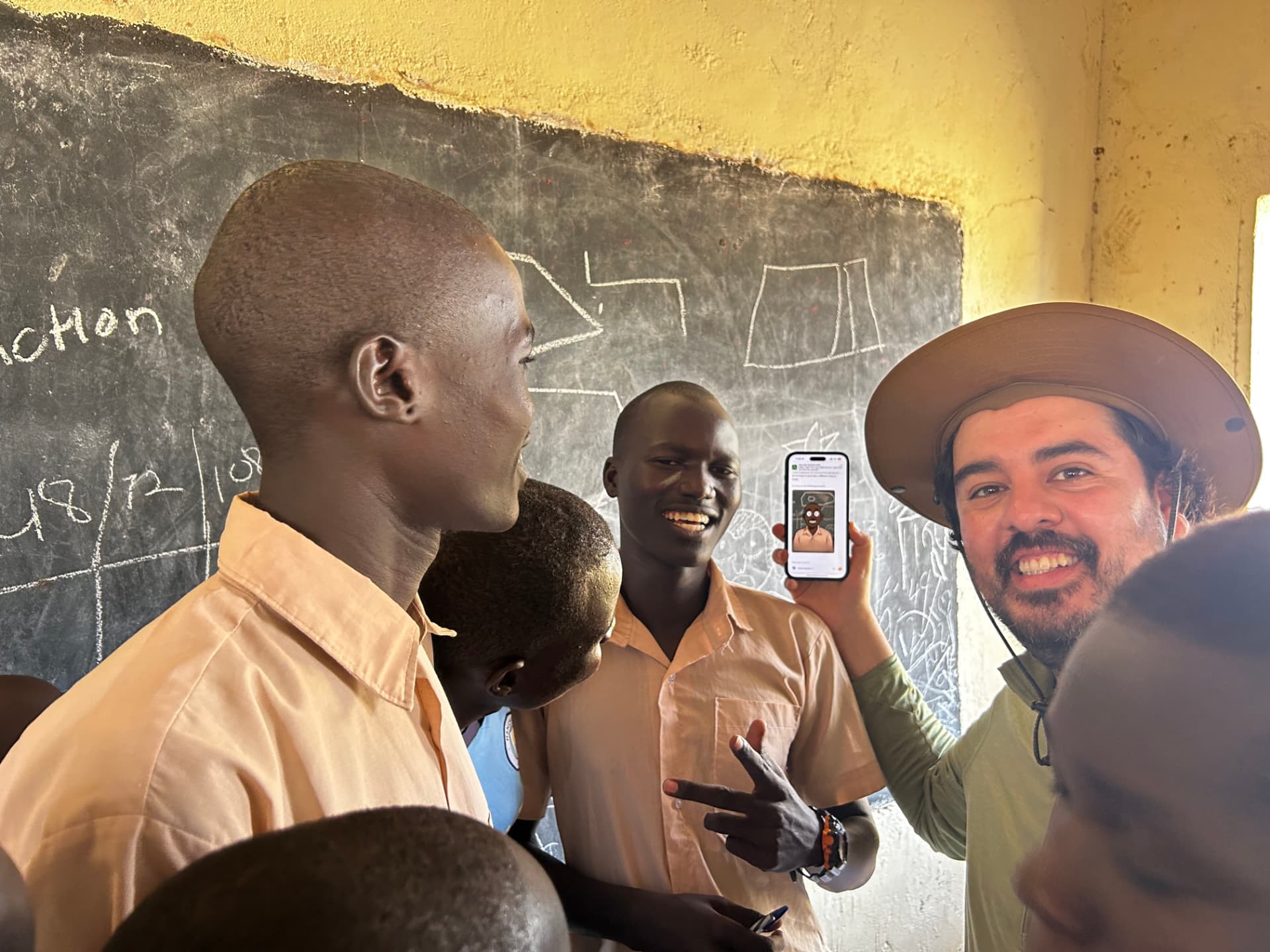 Victor Aldana showing students an AI demo on a phone in a Kenyan classroom
